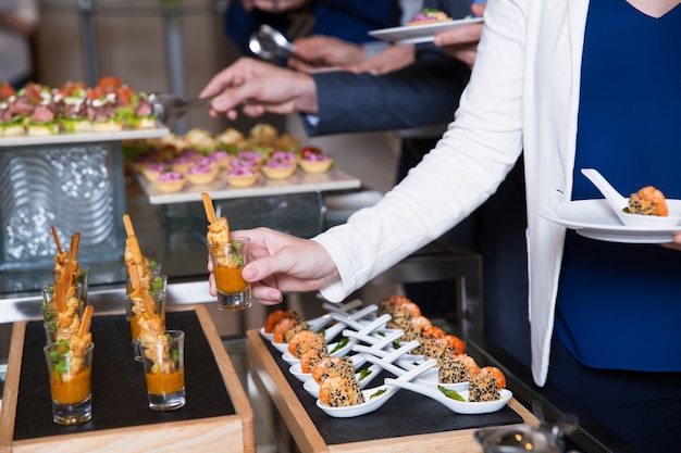 Free photo cropped woman taking snack from buffet table