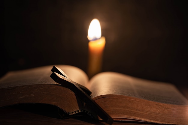 Cross with bible and candle on a old oak wooden table. 