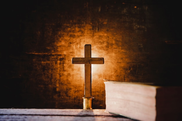 Cross with bible and candle on a old oak wooden table. 