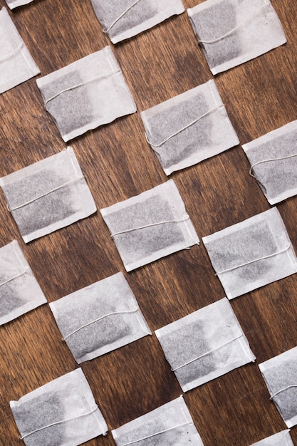 Crossed white tea bag on wooden textured backdrop