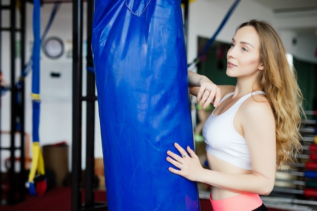 Free Photo crossfit fitness woman boxing with blue punching bag at gym