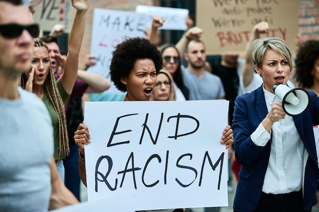 Free photo crowd of people protesting against racism on the streets focus is on african american woman holding banner with end racism inscription