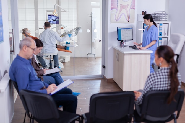 Free photo crowded stomatology waiting area with people filling form for dental consultation