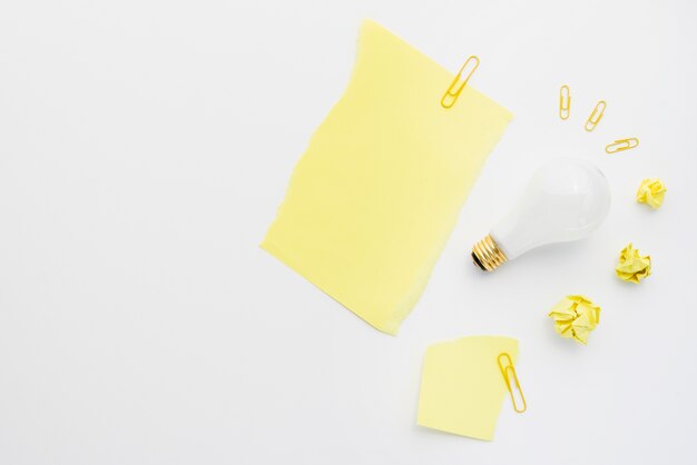 Crumpled paper ball with white light bulb and paperclip on white background