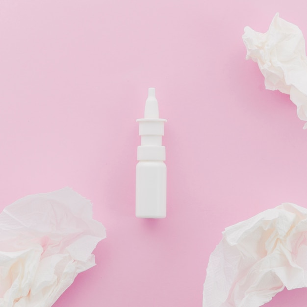 Crumpled white paper and dropper bottle on pink background