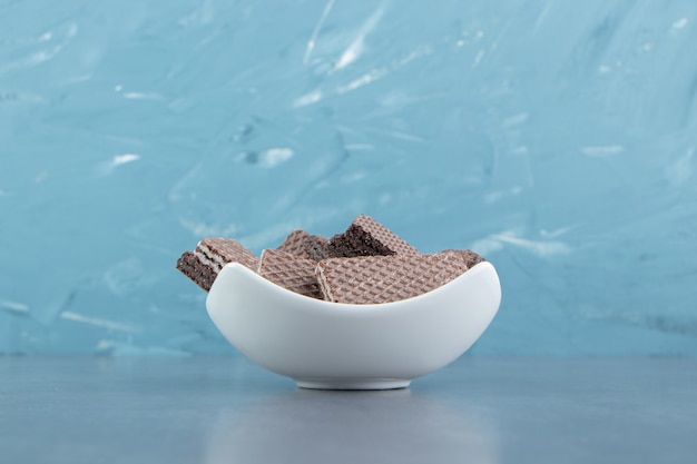 Crunchy chocolate waffles in white bowl.