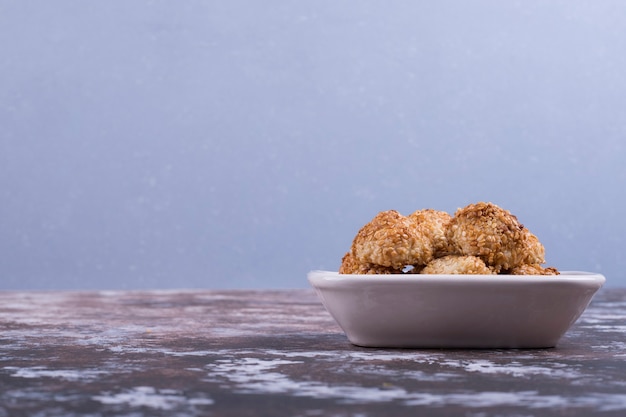 Free Photo crunchy cookies in a white ceramic saucer on blue.