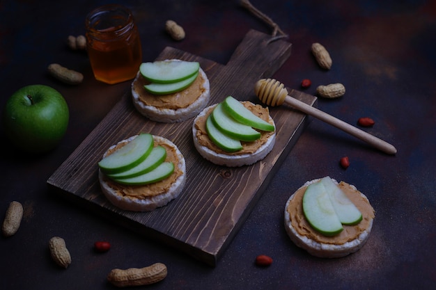 Free photo crunchy natural peanut butter sandwich with rice cake bread and green apple slices and honey.