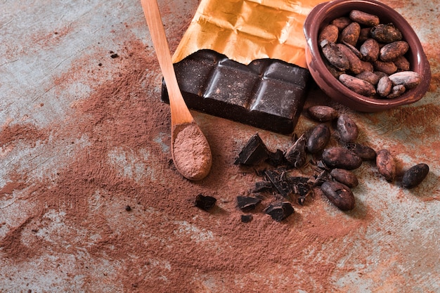 Crushed broken chocolate and cocoa beans bowl on rustic backdrop