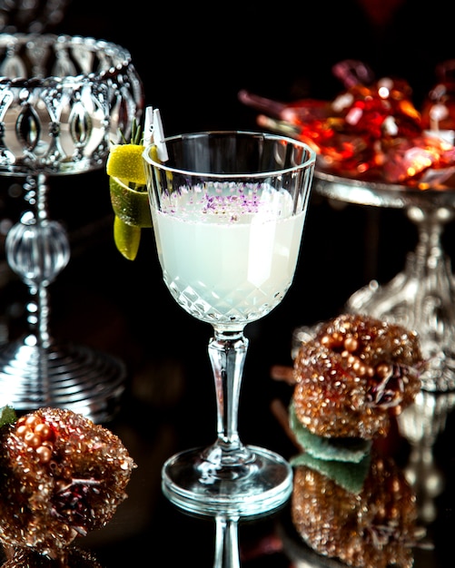 A crystal glass with white cocktail garnished with lemon zest