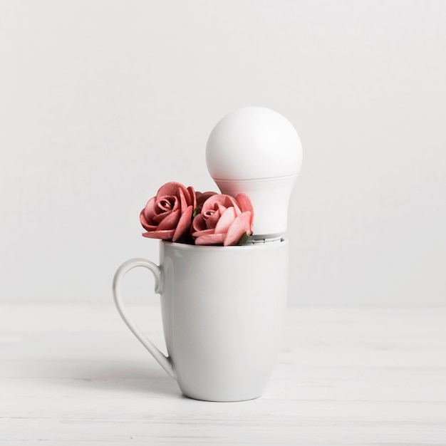 Free Photo cub with beautiful roses and a light bulb