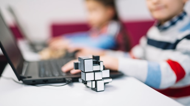 Free photo cube puzzle in front of girl using laptop on white desk