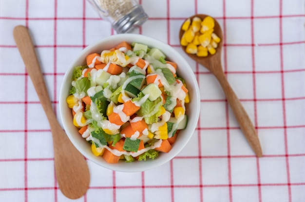 Free photo cucumber salad, corn, carrot and lettuce in a white cup.