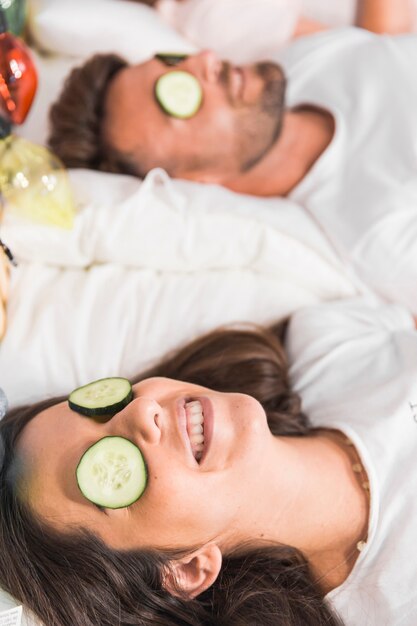 Cucumber slices over the couple's face on bed