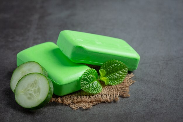 Cucumber slices and soap on dark background