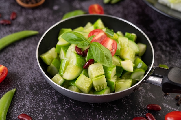 Cucumber stir-fried with tomatoes and red beans in a frying pan.