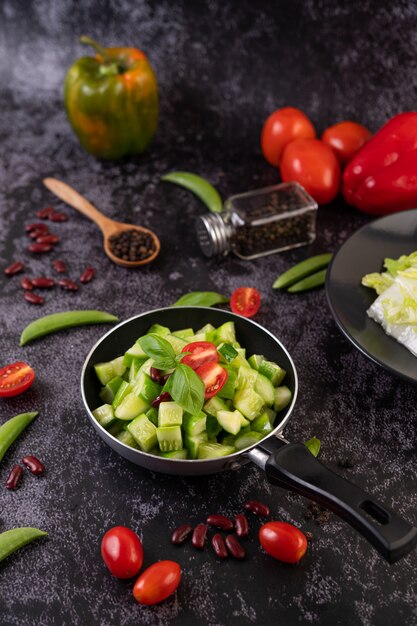 Cucumber stir-fried with tomatoes and red beans in a frying pan.