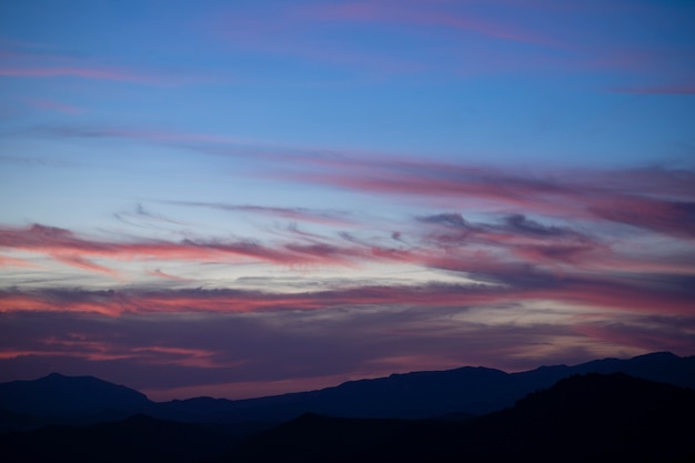 Cumulus sunset clouds with sun setting down on dark background