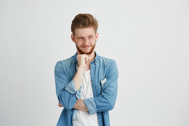 Cunning tricky young man thinking looking in side with hand on chin.