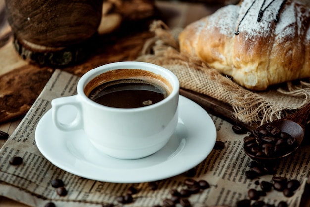 cup of americano coffee placed on newspaper