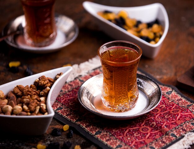 Cup of aromatic tea and bowl with nuts