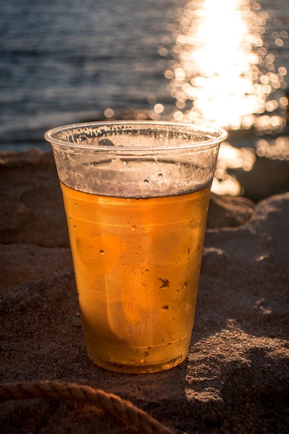 Free photo cup of beer on the background of the ocean during the sunset