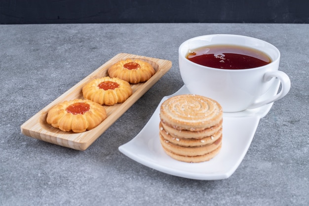 Free photo cup of black tea with delicious biscuits on marble surface