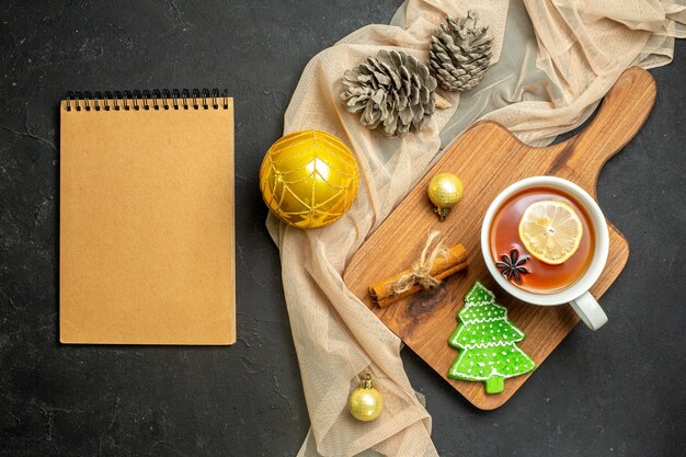 A cup of black tea with lemon and cinnamon limes new year decoration accessories on wooden cutting board