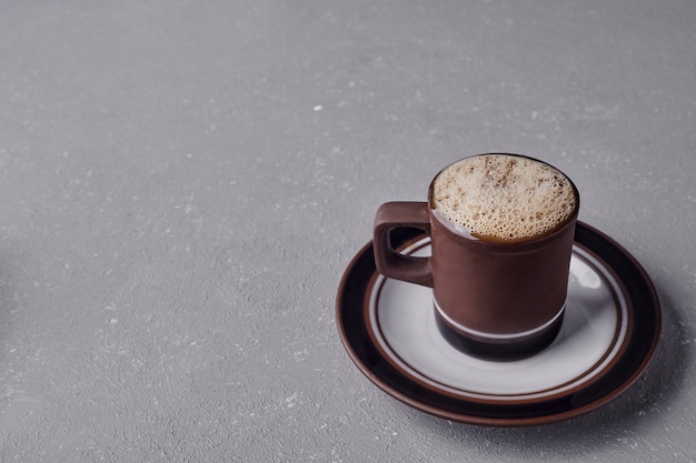 A cup of cappuccino on grey background.