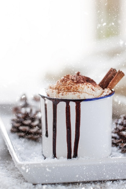 Free photo cup of chocolate with cream and two cinnamon sticks