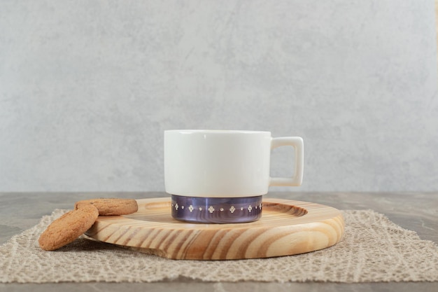 Cup of coffee and biscuits on wooden plate