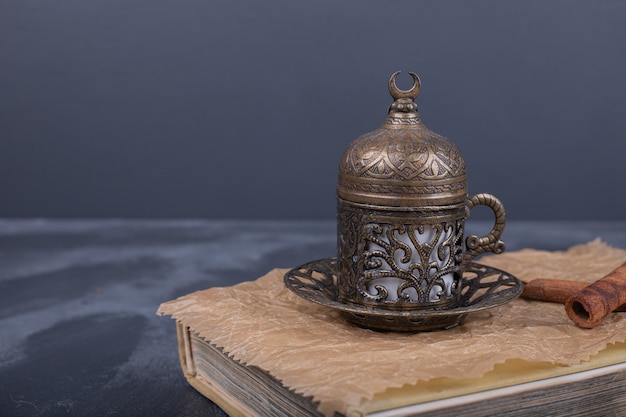 A cup of coffee and cinnamon on top of book.