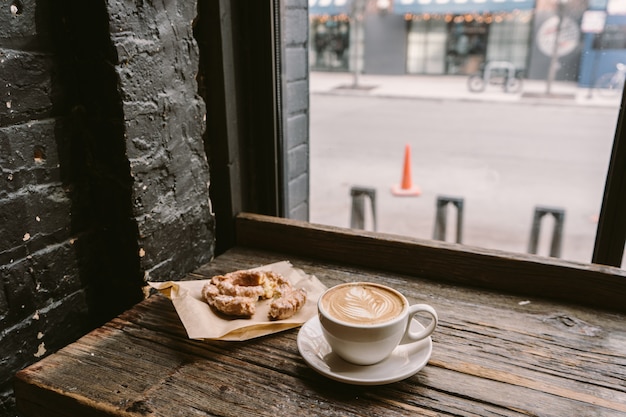 Free Photo cup of coffee next to a cookie put on the windowsill