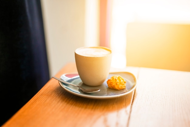 Cup of coffee and cookie on wooden table