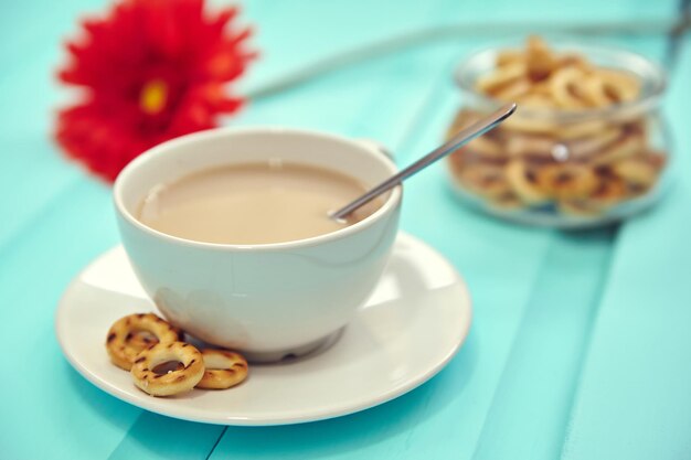 Cup of coffee on old wooden table top view with spring fresh red flowers with big plate of russian bubliks