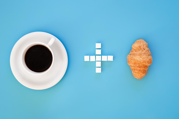 Free photo a cup of coffee a plus sign made of sugar and a croissant flat lay