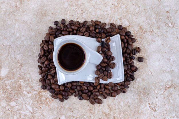 Free Photo a cup of coffee on a saucer sitting on a pile of coffee beans 