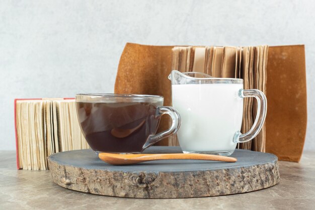 Cup of coffee, spoon and milk on wood piece. 