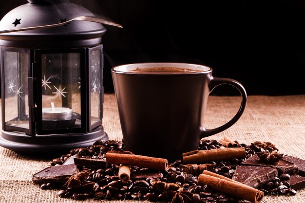 Cup of coffee stands on coffee beans and chocolate