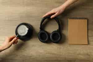 Free photo a cup of coffee with headphones and a notebook on a wooden background