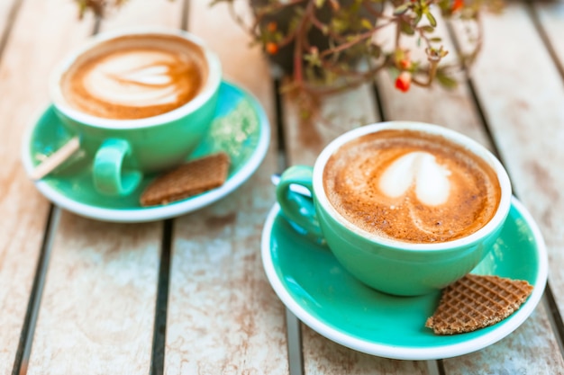 Cup of coffee with heart shape latte art on wooden table