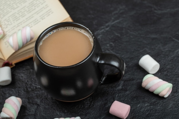 A cup of coffee with marshmallows and book. 