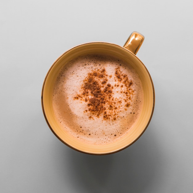 Cup of coffee with milk foam and cocoa powder on gray background