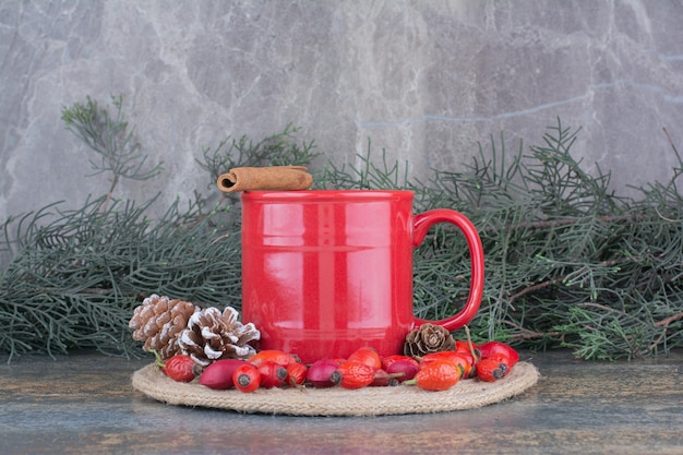 A cup of coffee with rosehips and pinecones on marble background . High quality photo