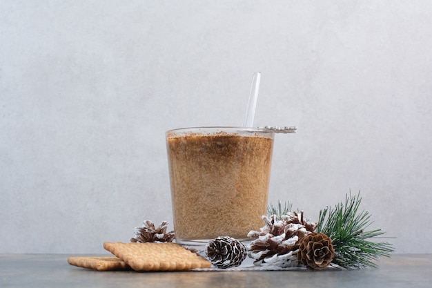 Cup of coffee with tasty crackers and pinecones on marble background. High quality photo