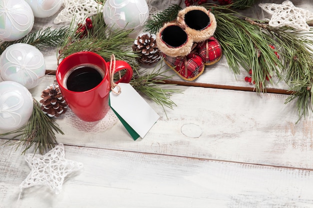 Free photo cup of coffee on the wooden table with a empty  blank price tag and christmas decorations.