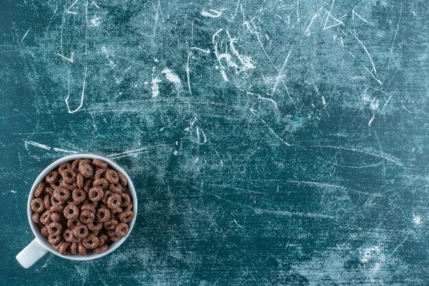 A cup of corn rings , on the blue table. 