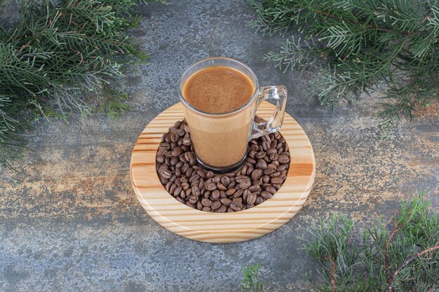 A cup of delicious coffee with coffee beans on wooden board. High quality photo