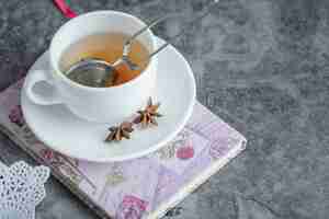 Free photo a cup of delicious tea with star anise on white plate.