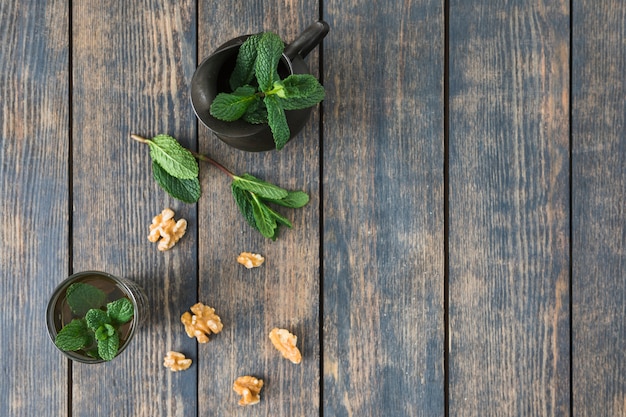 Free photo cup of drink near pitcher, plant twigs and nuts on table